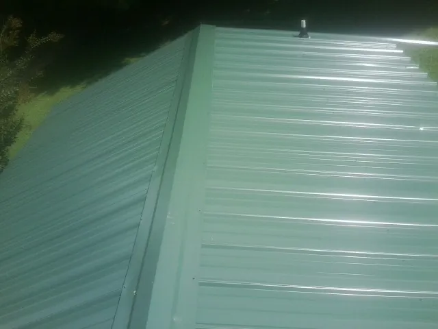 New green metal panels meeting at the ridge of a roof — Flat Roof Repair work by our crew in Union
