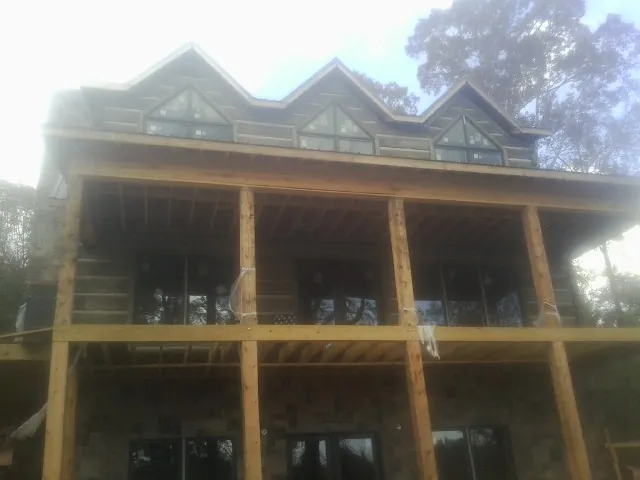 Dormers and porch framing on a large log home under construction — Roof Coating work by our crew in Union