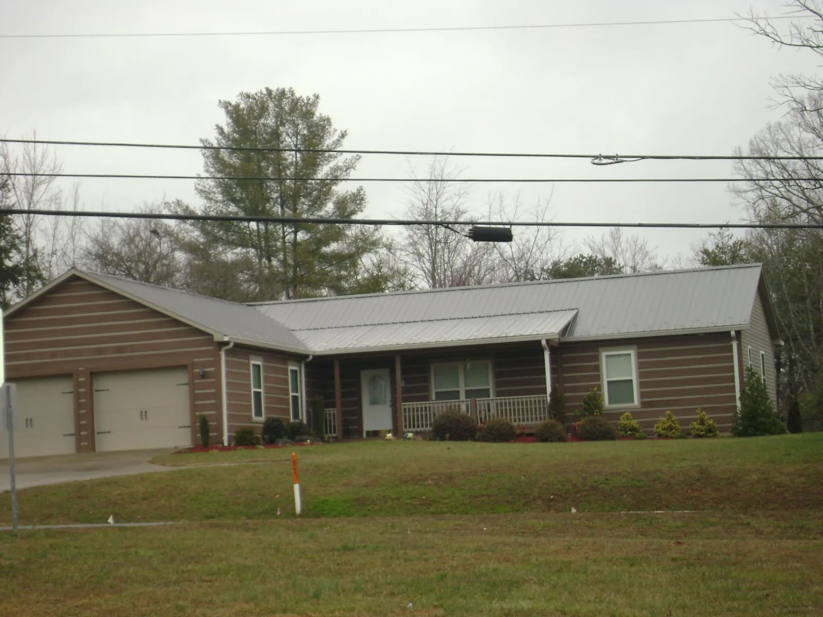 Gray metal roof on a log sided ranch home with a front porch in Union